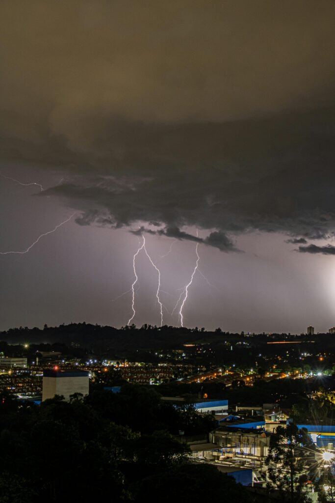 A cityscape captured at night highlighting an intense lightning strike over the urban skyline.